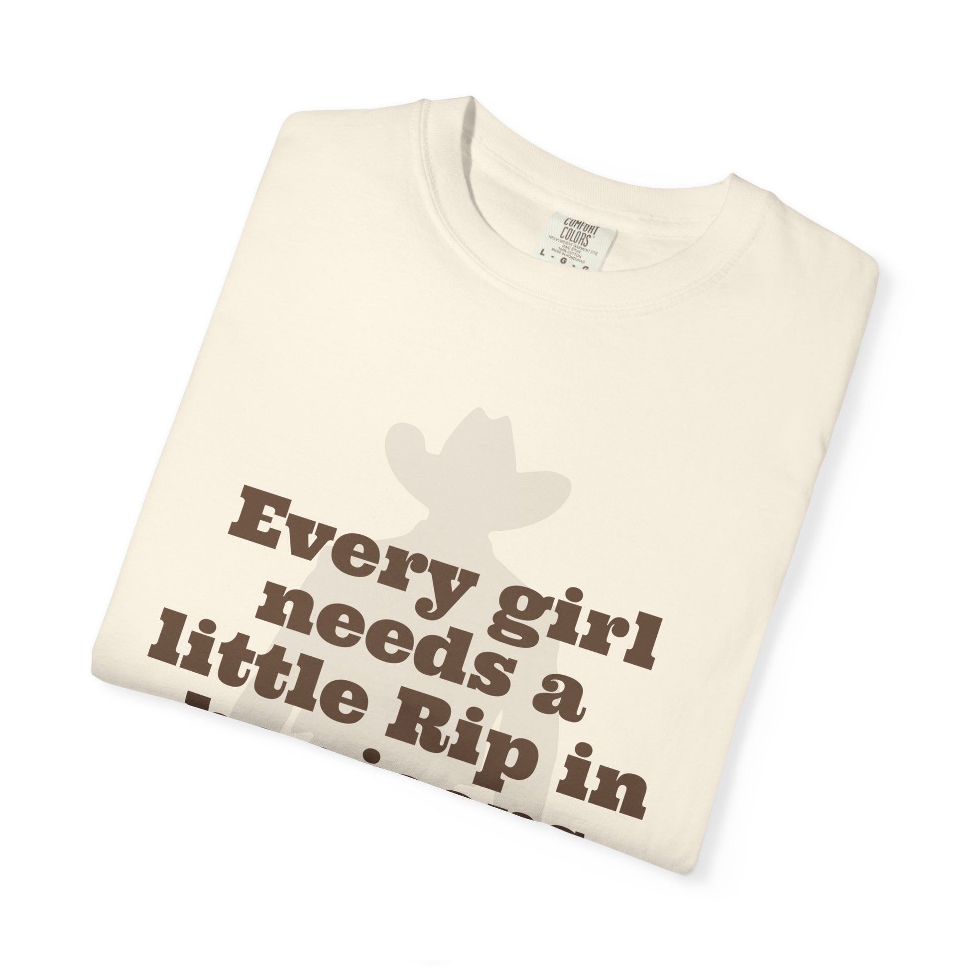 Folded t-shirt with text 'Every girl needs a little Rip in' on a white background