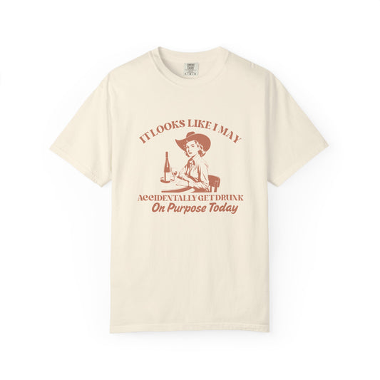Beige shirt with a cowgirl and text that says 'It looks like I may accidentally get drunk on purpose today' 